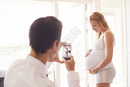 男人用手机上拍摄怀孕女友的照片图片