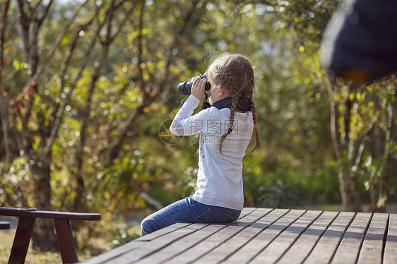 农村女孩坐在木板上透过望远镜看风景图片