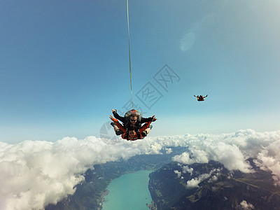 云层和风景上方的双人跳伞者肖像图片