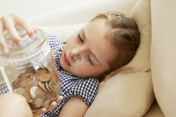 年轻女孩在沙发上拿着一罐钱思考的表情图片