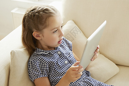 年轻女孩在沙发上休息用数字平板电脑图片