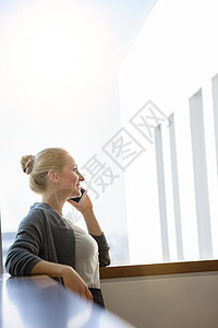 在办公室走廊打电话的年轻女商人图片