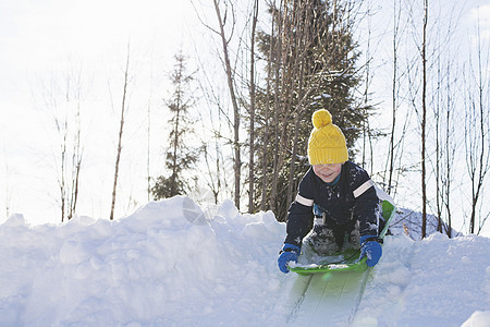 戴着黄色针织帽的男孩在白雪覆盖的小山上滑雪图片