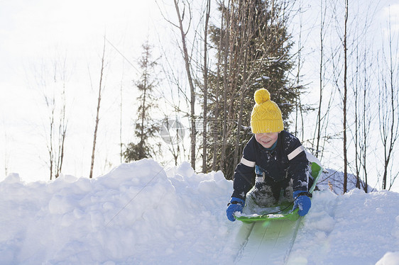 戴着黄色针织帽的男孩在白雪覆盖的小山上滑雪图片
