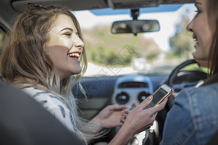 年轻女子与朋友一起开车手持智能机图片