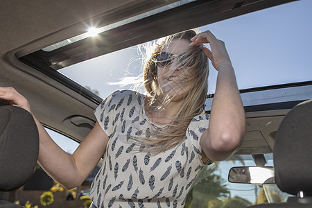 年轻女士将头伸出汽车天窗图片