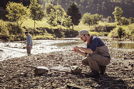 年轻的渔民在河流中用棍子叉鱼图片