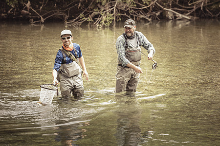 两个渔民在及膝的河里用网兜捕鱼图片