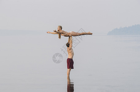 海滩上的年轻男人把女人举过头顶图片