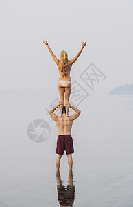 海滩上的年轻女人站在男的肩膀上背影图片