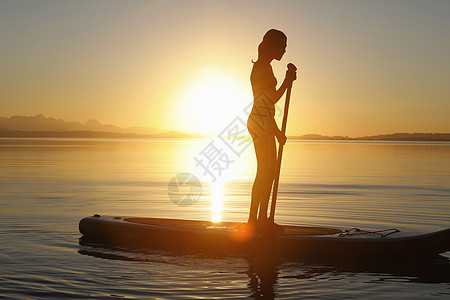 在日落时年轻女孩站在船上图片