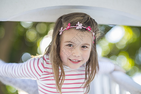 学龄前女童站在花园攀爬架上微笑图片