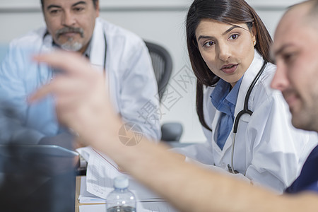 坐在桌边的一组医生在讨论病人的X光片图片