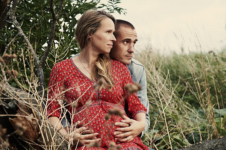 坐在树干上的浪漫成年怀孕夫妇图片