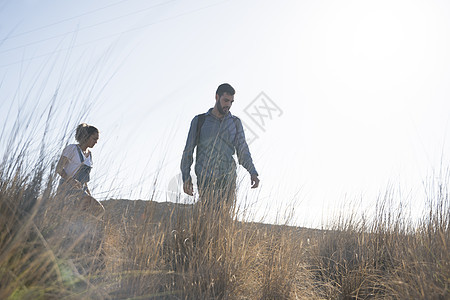 在西班牙加那利群岛拉斯帕尔马的草丛上徒步旅行的年轻夫妇图片