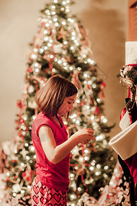 圣诞树前的女孩在拆礼物图片