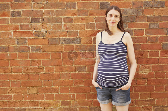 砖墙对怀孕的中年成妇肖像图片