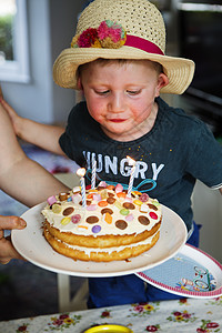 男孩在吹生日蛋糕上的蜡烛图片