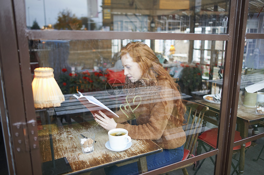 透过咖啡店窗口看到一个在看书的女人图片