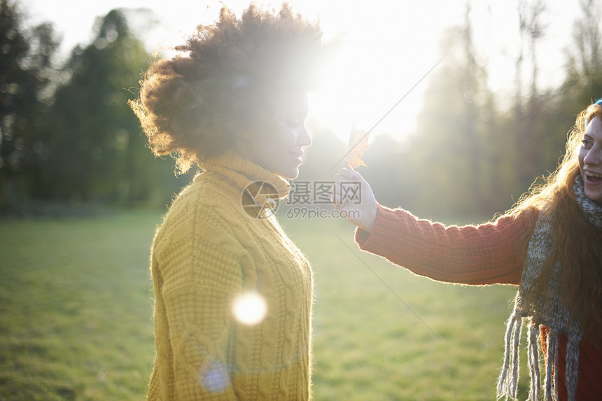 女人拿着叶子给朋友看图片