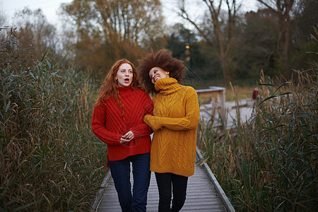 2名年轻妇女在沿农村道路行走时手举臂路图片