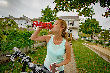 年轻女孩在自行车上喝水图片
