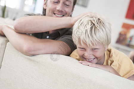 父亲和儿子在沙发上大笑图片