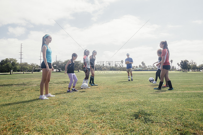 在校运动场上女学生面对面训练踢足球图片