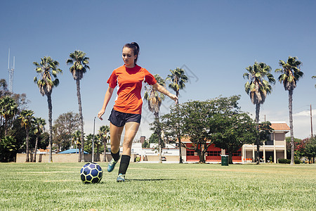 女学生在学校运动场上踢足球图片