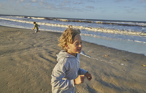 南美洲乌拉圭罗沙波罗尼奥海滩上的男孩在拍打着的海浪中玩耍图片