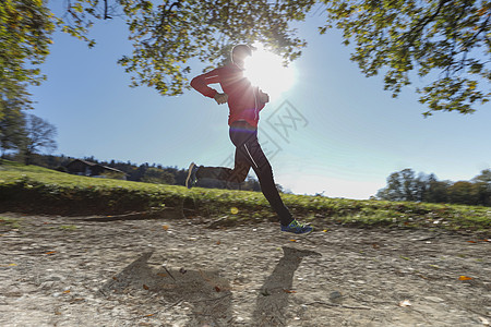 成年男跑步下阳光照的农村泥土田径图片