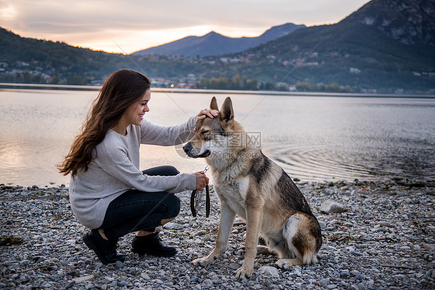 意大利伦巴迪Vercurago河岸的年轻女子宠爱狗图片