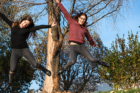 两名年轻女子在意大利伦巴第Calolziocorte的woodland空中跳跃图片