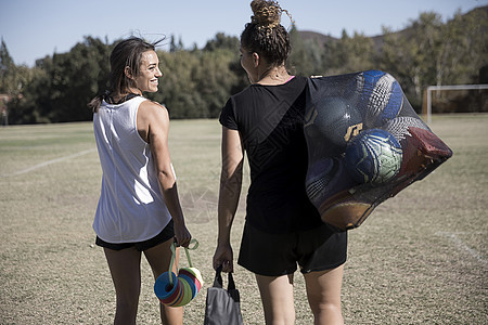 足球场上的妇女携带足球在网袋中图片