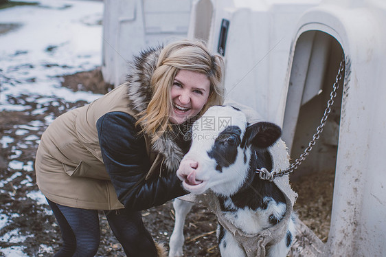 在冬季风景中年轻女与奶牛的肖像图片