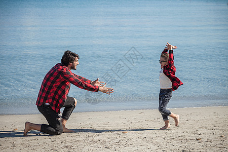 父亲和儿子在海滩上跑向父亲图片
