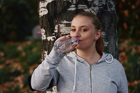 年轻女子在公园饮用水瓶装培训的肖像图片