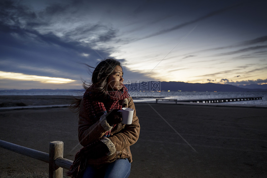 分西班牙加泰罗尼亚塔拉戈纳一名裹着围巾的年轻女子从海滩上回头望去