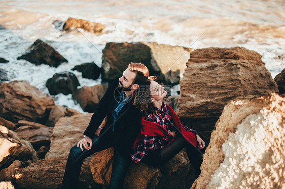在乌克兰敖德萨州奥海滩岩石上背靠坐着的浪漫中成年夫妇图片