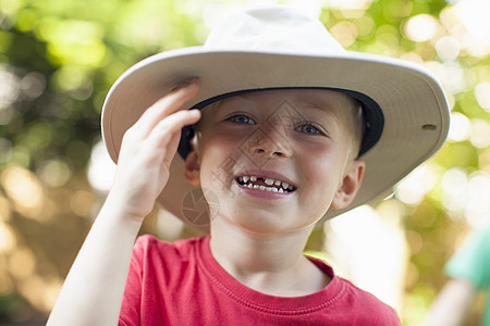 在阳光明媚的森林里戴着帽子的男孩图片