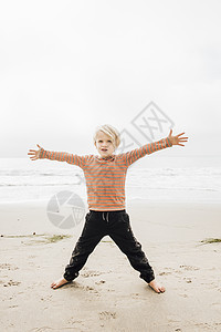 小男孩在海滩上张开双臂图片