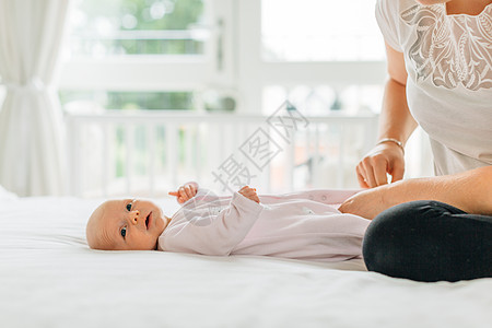 坐在床上的年轻女子和边上的婴儿图片