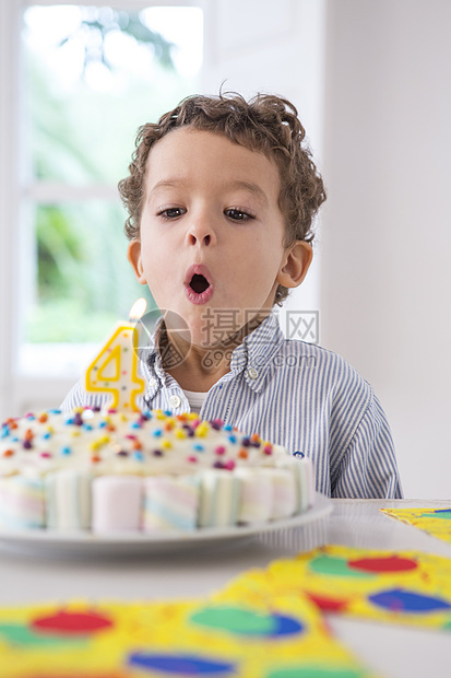 男孩吹灭生日蛋糕上的蜡烛图片