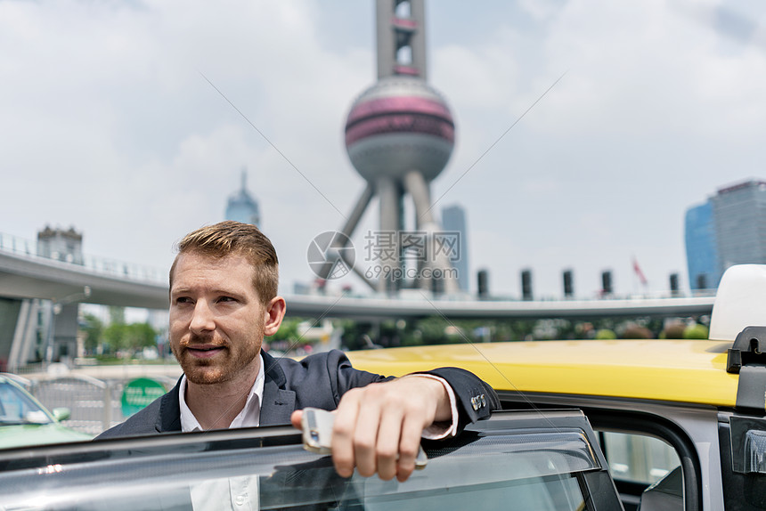 在上海金融中心从黄色出租车下的青年商人图片