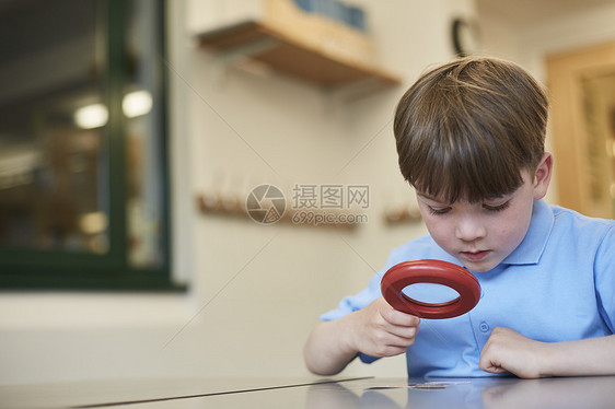 小学生在课堂上拿着放大镜观察的男生图片