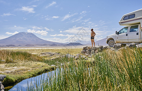 车智汇站在岩石上的成熟男子在娱乐车旁看风景玻利维亚南美洲背景