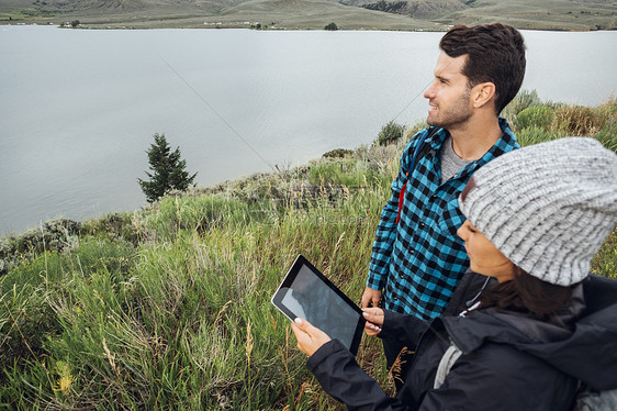 站在美国科罗拉多州湖边用数字平板的夫妇图片
