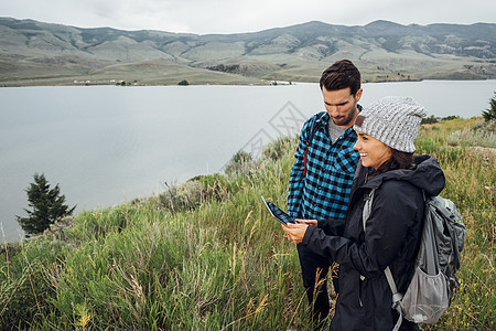 站在美国科罗拉多州湖边用数字平板的夫妇图片