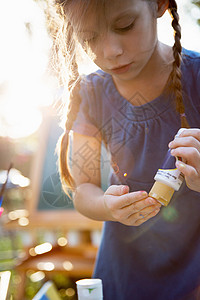 女孩在花园里把涂料挤到手指上图片