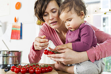 厨房里的母亲和宝宝拿着西红柿图片